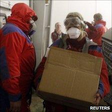 Rescue workers in protective gear carry supplies at the Geirland farm near Kirkjubaejarklaustur