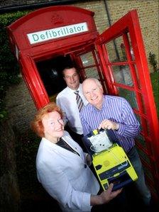 Red phone box and people with heart defibrillator