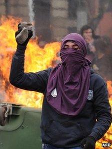 A student throws a stone at riot police officers during a protest against the government of President Sebastian Pinera and a new education law in Santiago, Chile on August 4, 2011.