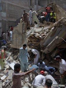 Rescuers look through the rubble of the building which collapsed in Karachi on 4 August 2011