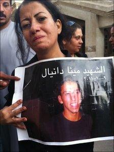 Mary Daniel holds up a picture of her brother Mina Daniel. Photo by Hamada Abu Qammar