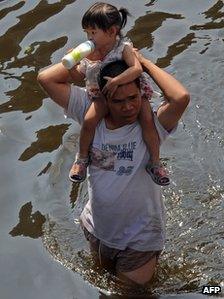 A man carries a girl through floodwater in Bangkok