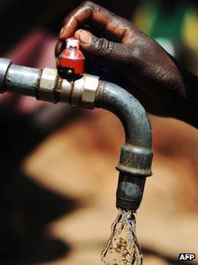 A hand turning on a tap with running water