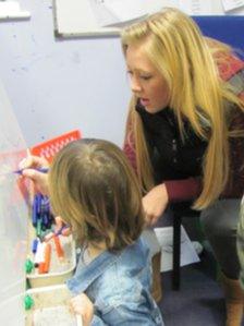 Teenager and toddler writing on board