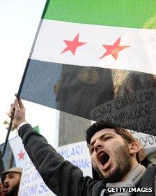 A man holds a pre-Baath Syrian flag as Turkish and Syrian protesters shout slogans in Istanbul.