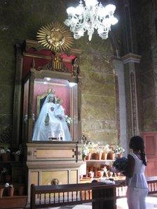 Woman standing, looking up at a shrine inside a church