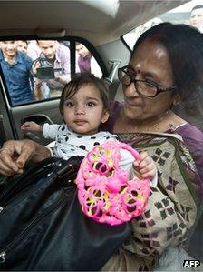 One year old Aishwarya Bhattacharya (C) is held by her grandmother (R) in a car shortly after her arrival at IGI airport in New Delhi on April 24, 2012.