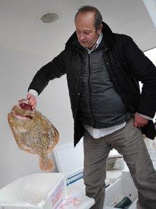 Rex Goldsmith holds up a fish in the back of his delivery van