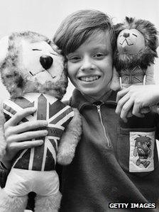 February 1966: Leo Hoye, the son of commercial artist Reg Hoye, the man who designed the world cup mascot Willie the Lion, holding mascot toys.