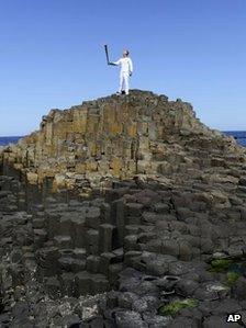 Peter Jack holds the Olympic torch aloft at the Giant"s Causeway