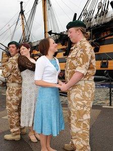 Cast members from Much Ado About Nothing with HMS Victory in the background