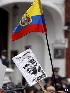 Supporters of Julian Assange hold up a placard and the flag of Ecuador outside the Ecuadorean Embassy in London