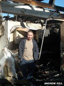 Andrew stands in the wreckage of his bungalow