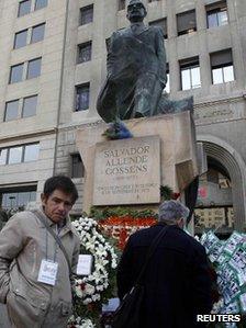 Flowers are left at a statue of Salvador Allende