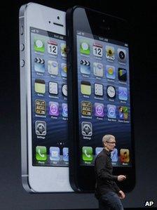 Tim Cook speaks in front of an image of the iPhone