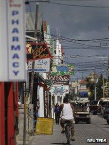 A man rides his bicycle past stores by the main square in San Pedro November 15