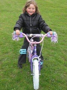 April Jones on her pink and purple bicycle
