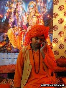 Devya Giri, leader of the new women's order, on a mobile phone in front of a picture of Hindu gods Shiva and Parvati