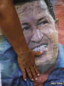 A supporter of Venezuelan President Hugo Chavez touches a poster of him at a local election rally, December 2012