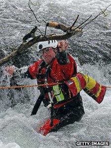 A member of a mountain rescue team moves a branch that has been caught on fast-flowing river water as they help in the search for April Jones