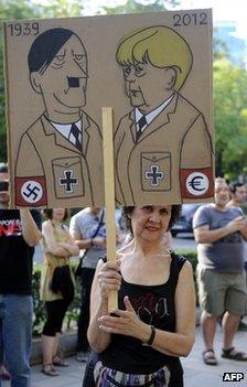 A protester in Madrid holds a placard likening German Chancellor Angela Merkel to Hitler, 6 September 2012