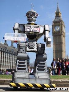 A mock 'killer robot' distributes promotional literature calling for a ban on fully autonomous weapons in Parliament Square