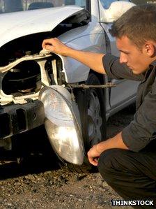 man inspects wreckage of car