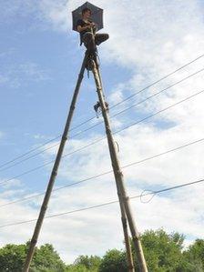 An environmental activist on top of a tripod made of trees in the US in July