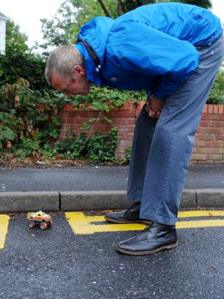 A resident looks at a toy car in the parking space