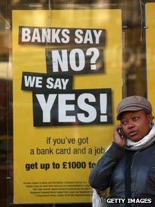 Woman stands by poster advertising loans