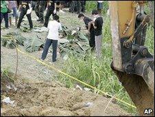 Police inspect the bodies in hillside grave in Ampatuan, Maguindanao province