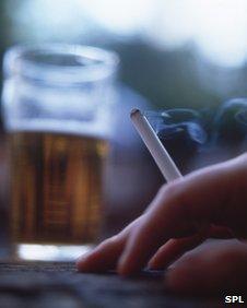 Person holding cigarette and pint of beer