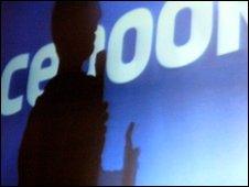 silouthette of someone in front of facebook sign