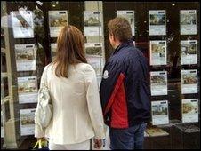 Two people look in an estate agent's window