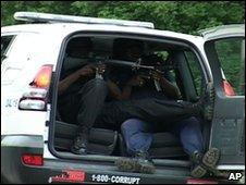 Jamaican police officers point their guns from inside a police vehicle in Kingston, Jamaica, 25 May 2010