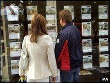 Two people look in an estate agent's window