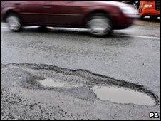 A car driving past a pothole