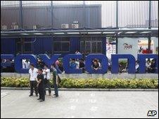 Staff gather at the company sign outside Foxconn's plant in Shenzhen on 26 May 2010