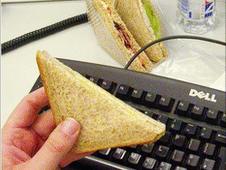 Eating a sandwich at a computer