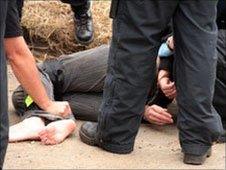 Police restrain a young woman outside the camp