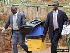 Police detectives with boxes of evidence from blast site