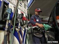 An employee fills a vehicle with petrol at a fuel station in New Delhi