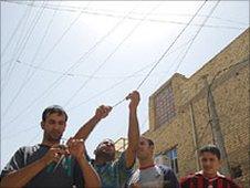 Ahmed (left) tries to attach an electrical cable to a generator