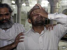 A man is comforted after the bombings in Lahore - 1 July 2010