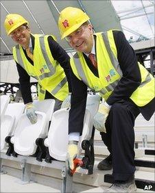 IOC President Jacques Rogge, right, and Sebastian Coe, chairman of the London Organising Committee for the Olympic Games help install the 2012th seat during a visit to the Olympic Stadium in London