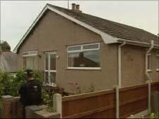 A policeman stands outside the house in Colwyn Bay