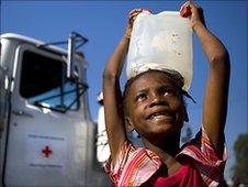 Girl carries water from Red Cross truck in camp near Port-au-Prince