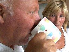 Derek Webster drinks a cup of tea as his wife Shirley looks on
