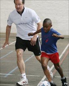 David Cameron playing football during a visit to a London school in 2009