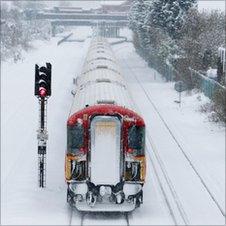 A train makes its way through the snow in Horley, Surrey as icy conditions cause further travel disruptions